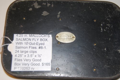 MALLOCHS SALMON FLY BOX. With 10 Gut-Eyed Salmon Flies, Full Dressed in Sizes #8 to 1. # #6 flies are double, rest are singles. Two of the flies are missing the gut eye. Marked on lid with Medallion: Mallochs/ Pat. No. 13561. 4.25 in. x 3.5 in. x 1/2 in. With 24 Large Clips. Japanned tin with black 